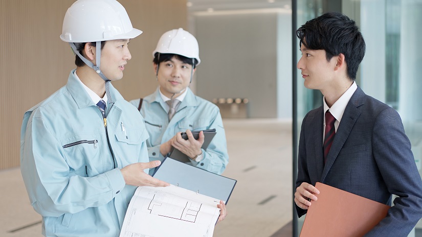 クライアントと打ち合わせをする作業服を着た男性