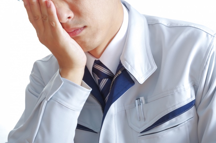 考え事をする作業服の男性