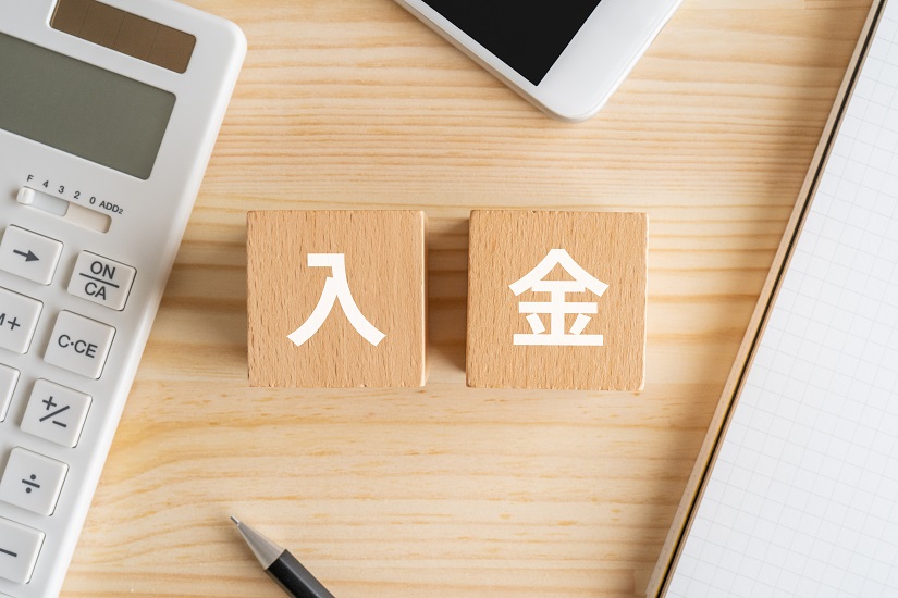 入金と書かれたブロック、電卓、スマホ、ノート、ペン
