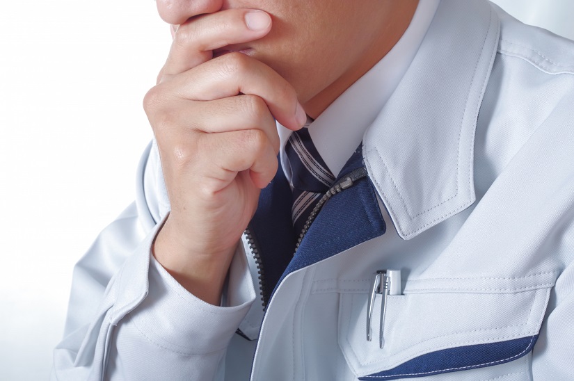 考え事をする作業服の男性