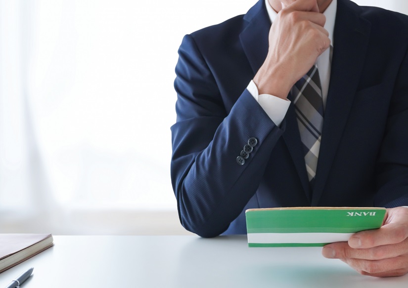 通帳　口座　考える　ビジネスマン