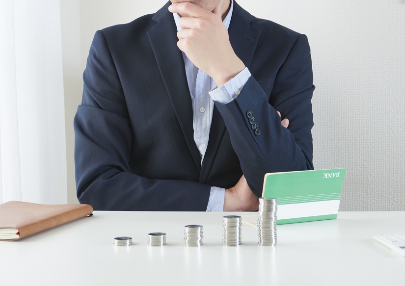 通帳を見て考えるビジネスマン