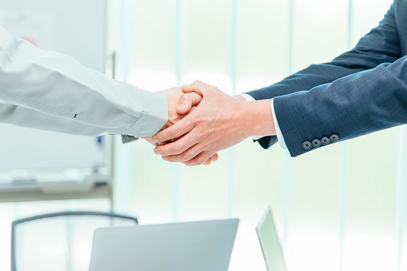 握手する作業着男性とビジネスマン