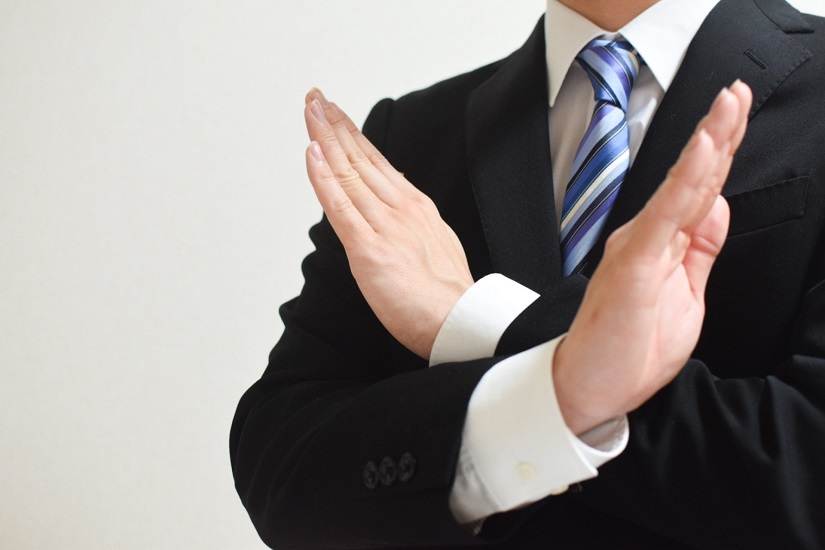 バツサインをするビジネススーツ男性
