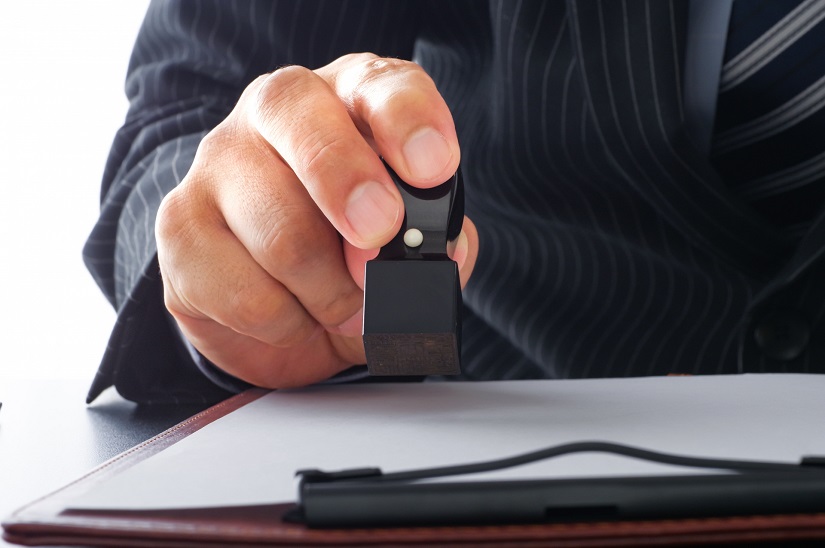 書類に角印を押すビジネスパーソン